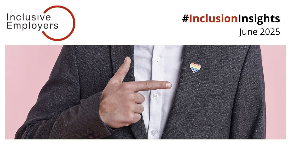 Person wearing a suit jacket with a rainbow heart pin, pointing to the pin. The image is part of Inclusive Employers' #InclusionInsights for June 2025