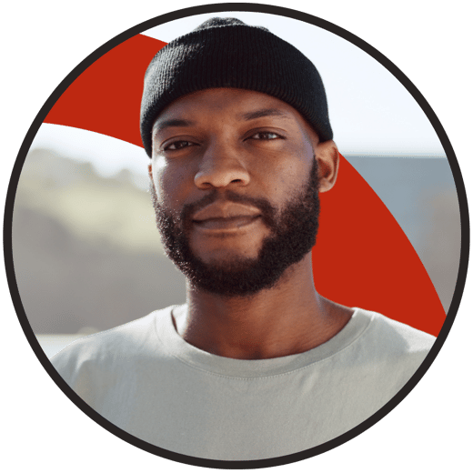 Person with a beard wearing a black beanie and white t-shirt against a backdrop featuring a red geometric element, all framed in a circular border with sea/sky visible in the background.