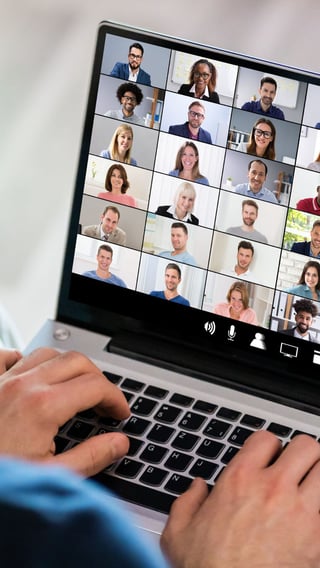 Image shows hands typing on a laptop, on screen is multiple people attending a webinar.